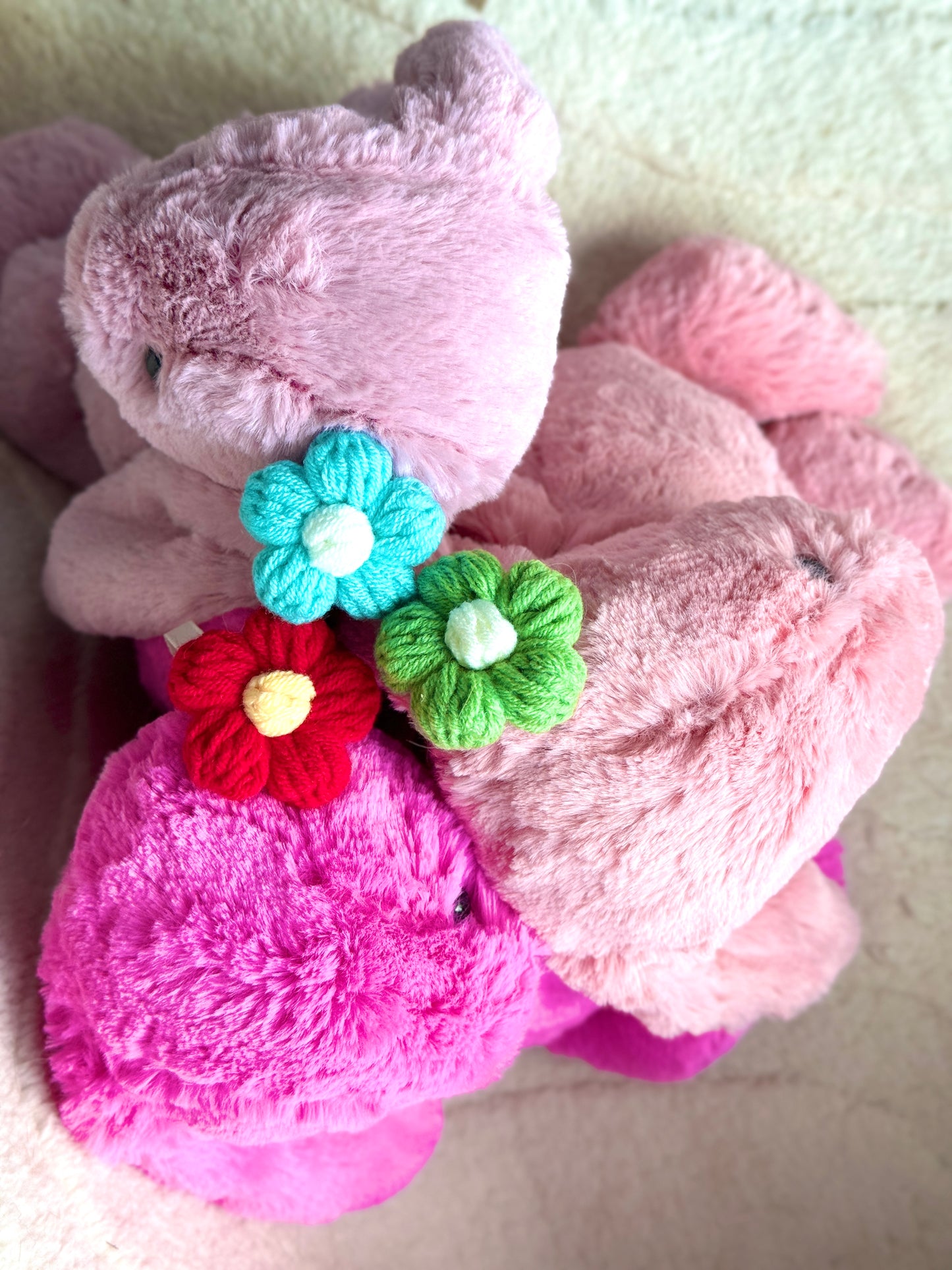 A top-down view of three Jellycat Bunnies lying on their backs with floppy ears spread out.