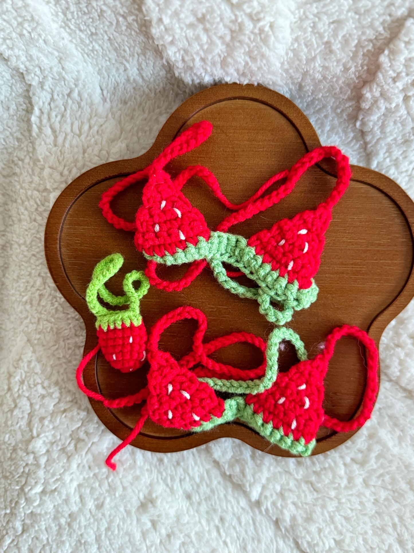 Flat lay of the full set: strawberry bikini top and tiny strawberry purse, placed on a wooden tray.