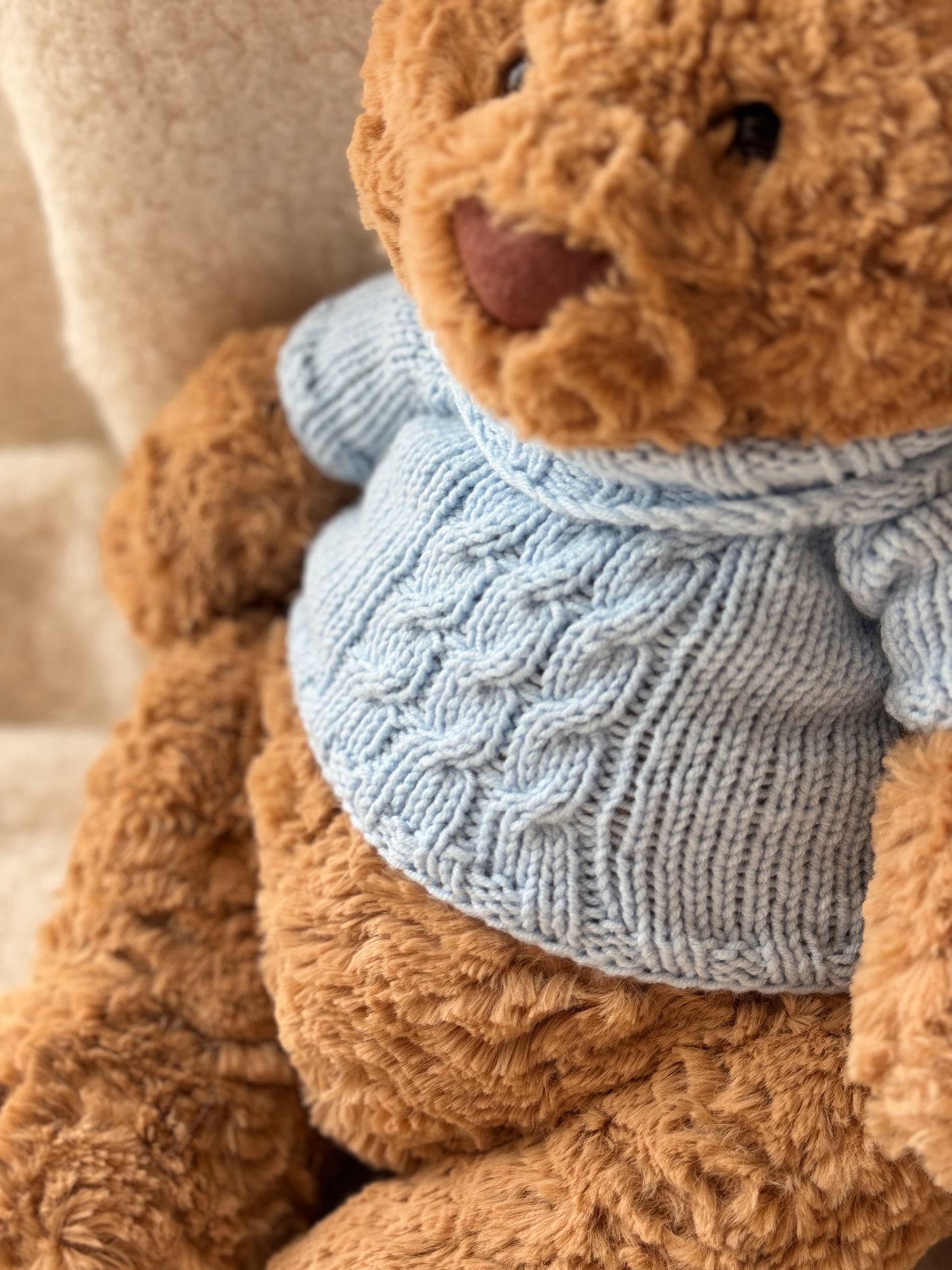 Jellycat Bartholomew Bear in a handmade blue knit sweater with classic cable texture and a soft high-neck design.