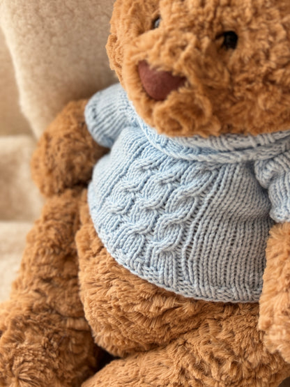 Jellycat Bartholomew Bear in a handmade blue knit sweater with classic cable texture and a soft high-neck design.