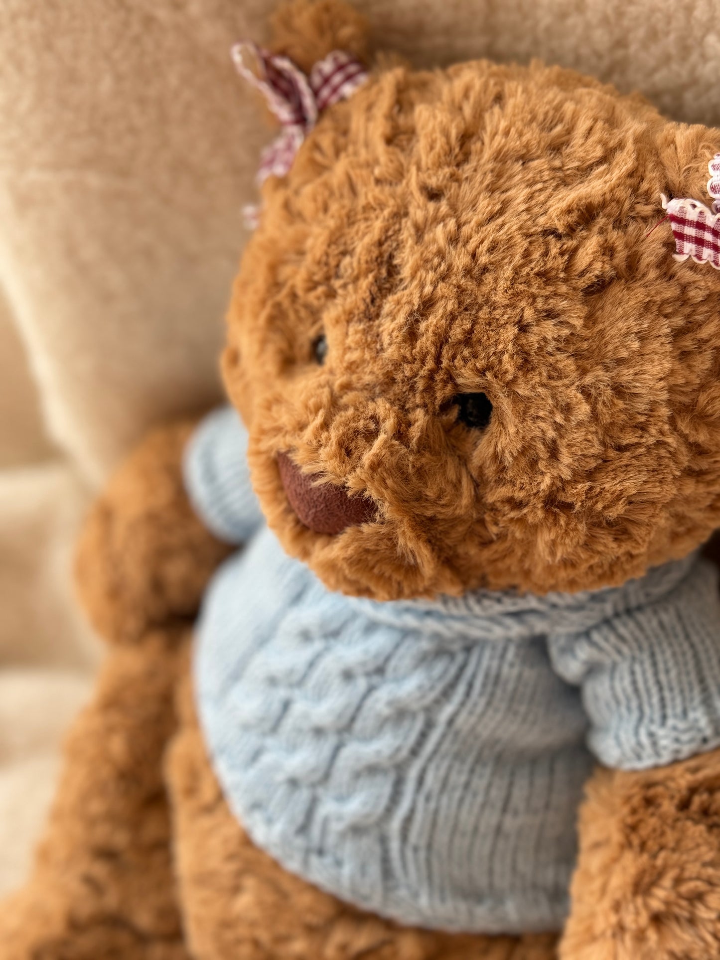 Close-up of Jellycat Bartholomew Bear wearing a blue cable knit plush sweater with a timeless handmade style.