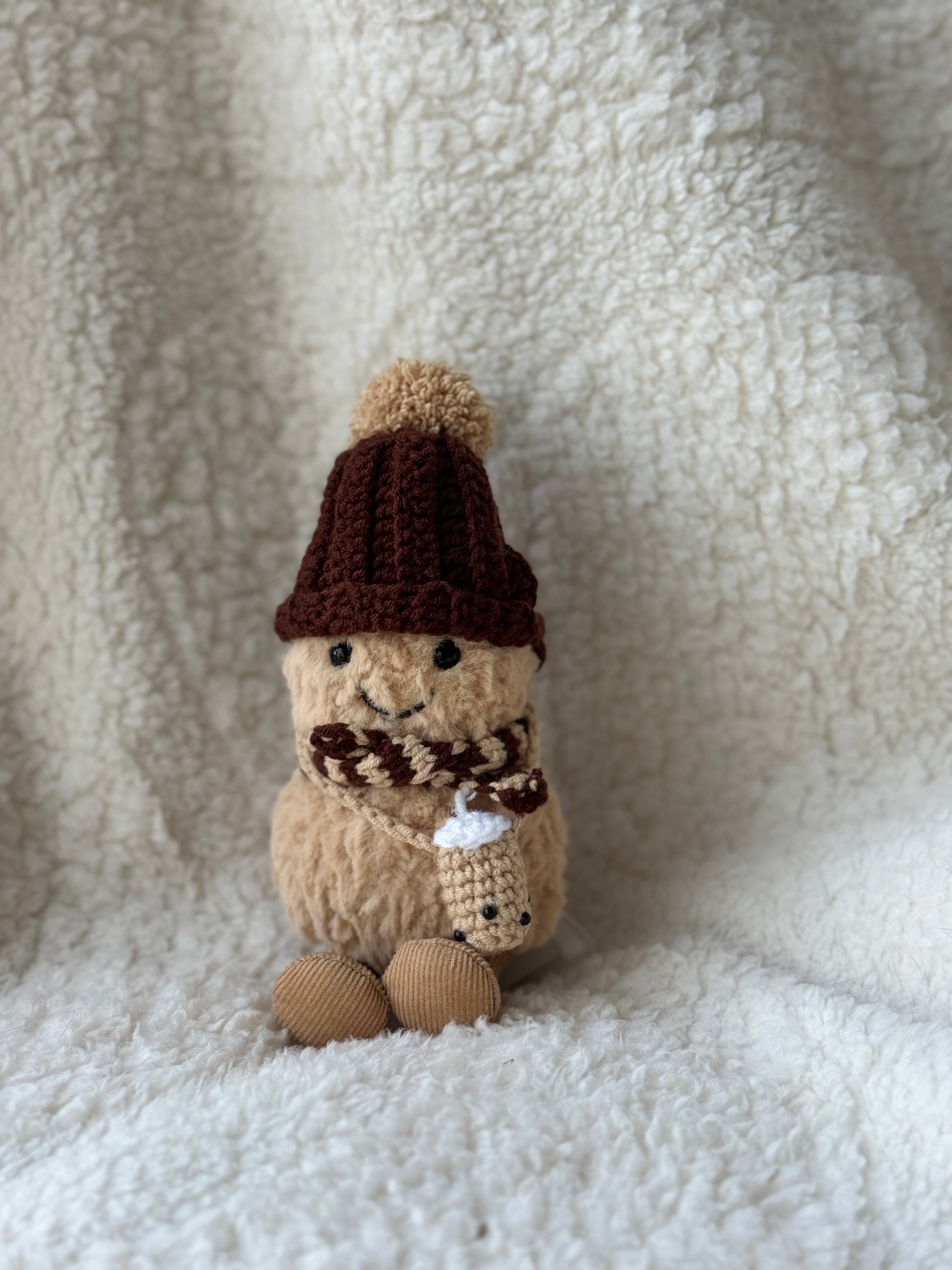 Jellycat Peanut wearing handmade crochet winter set with brown bobble hat, caramel pom-pom, striped scarf and tiny crochet boba tea cup, straight-on close-up