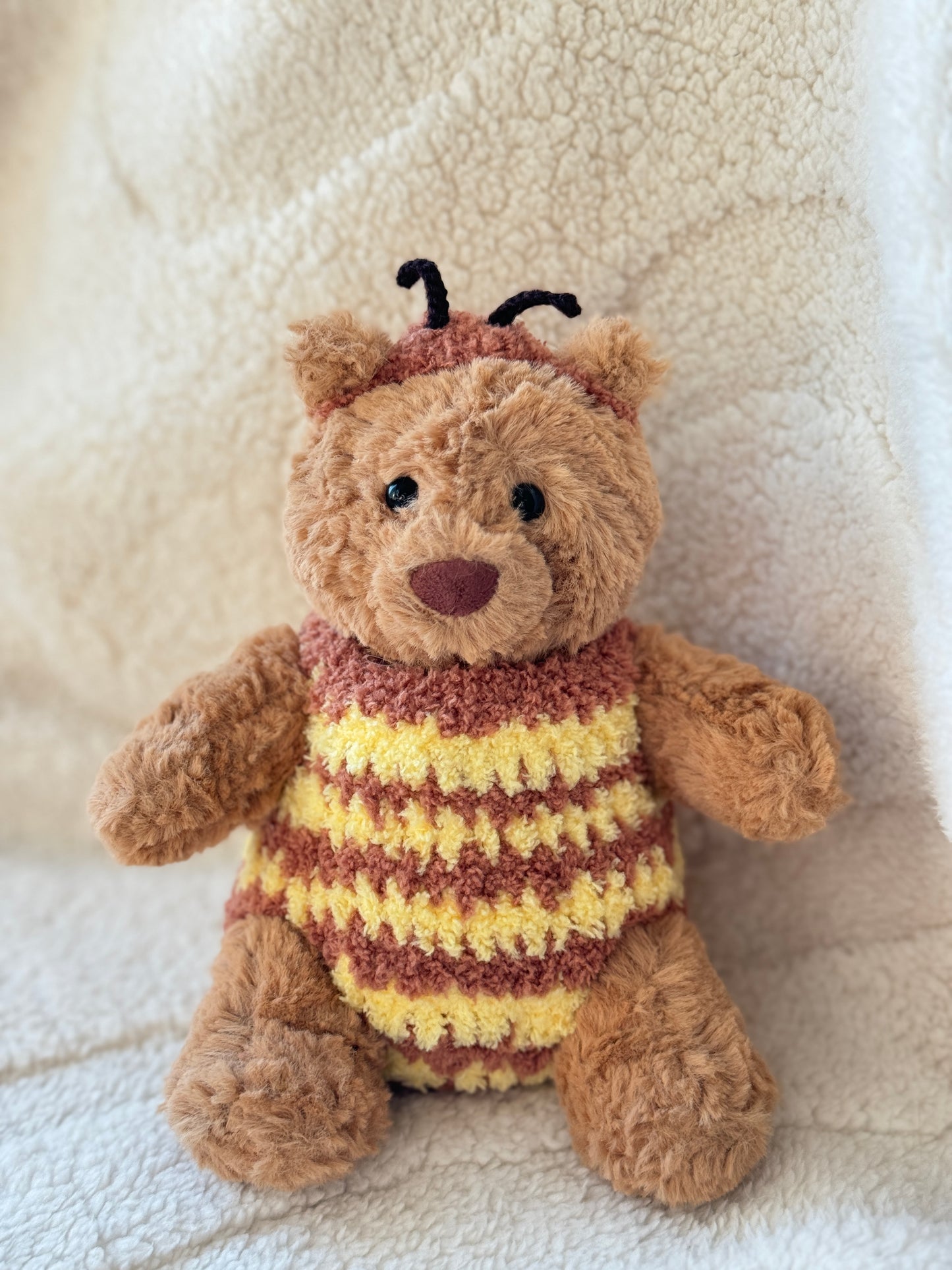 Jellycat Bartholomew Bear wearing a handmade bumble bee costume with honey yellow and brown stripes, tiny antennae, and soft white wings.
