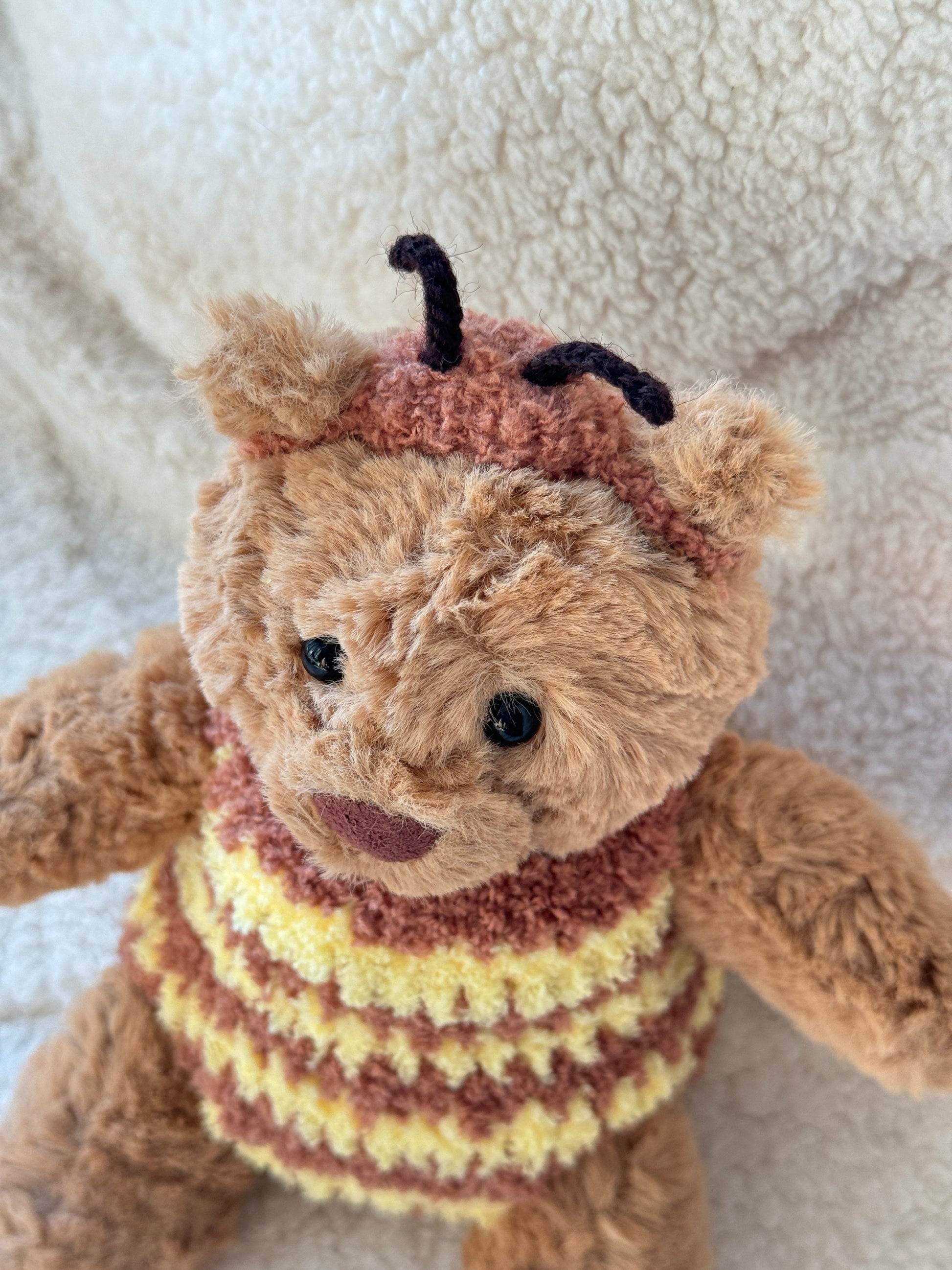 Close-up of Jellycat Bartholomew Bear in a fluffy bumble bee costume with tiny black antennae and textured crochet details.