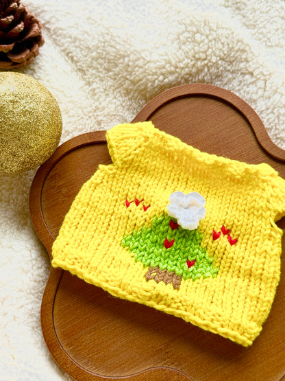 Flat lay of yellow knitted Christmas jumper with green Christmas tree design for 18cm plush toys.
