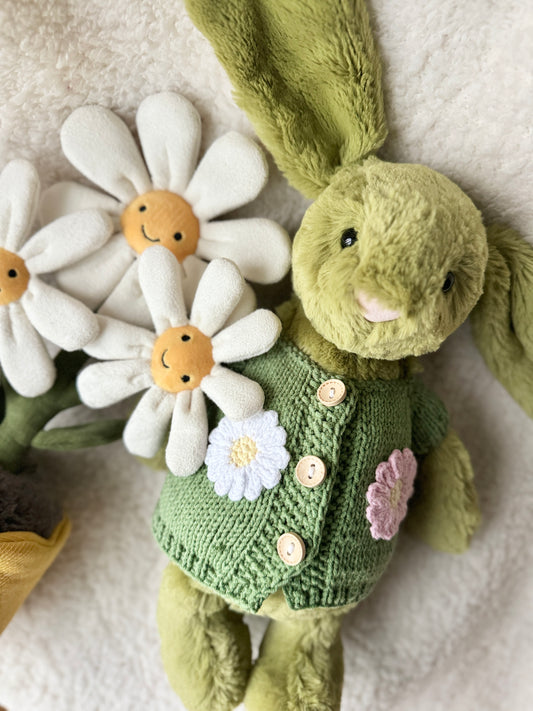 Handmade green knit cardigan on Jellycat Bashful Bunny close-up, showing white and pink crochet daisy appliqués and wooden buttons, Z Creations