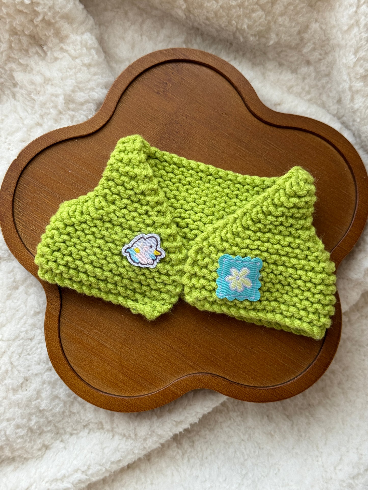 Handmade green crochet vest for 18cm Jellycat plush displayed flat on a wooden tray
