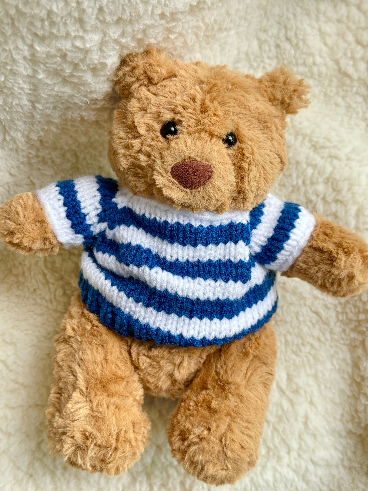 Close-up of a Jellycat teddy bear in a handmade navy blue striped knit sweater inspired by vintage maritime fashion.