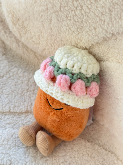 Close-up of a Jellycat Bean plush wearing a crochet floral hat with pink tulip details and soft cream yarn.